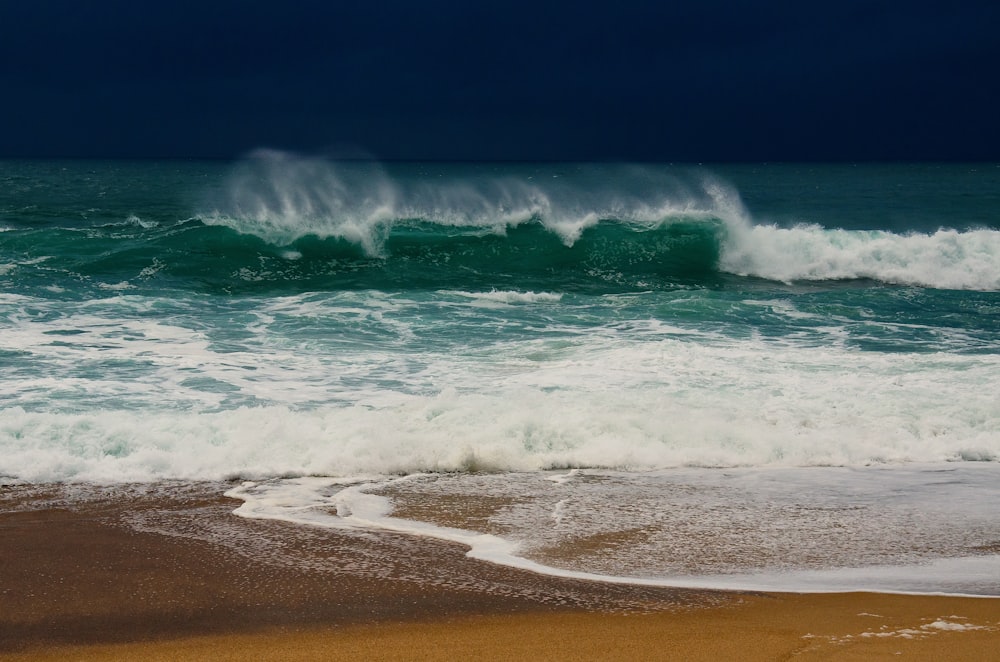 a large wave crashing into the shore of a beach