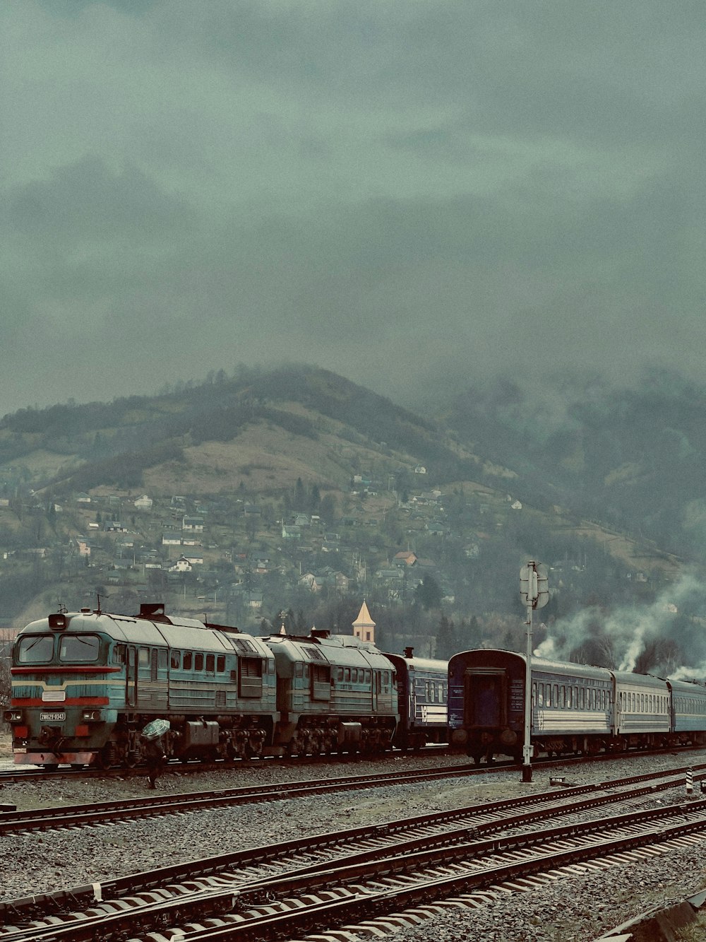 um trem viajando pelos trilhos do trem ao lado de uma montanha