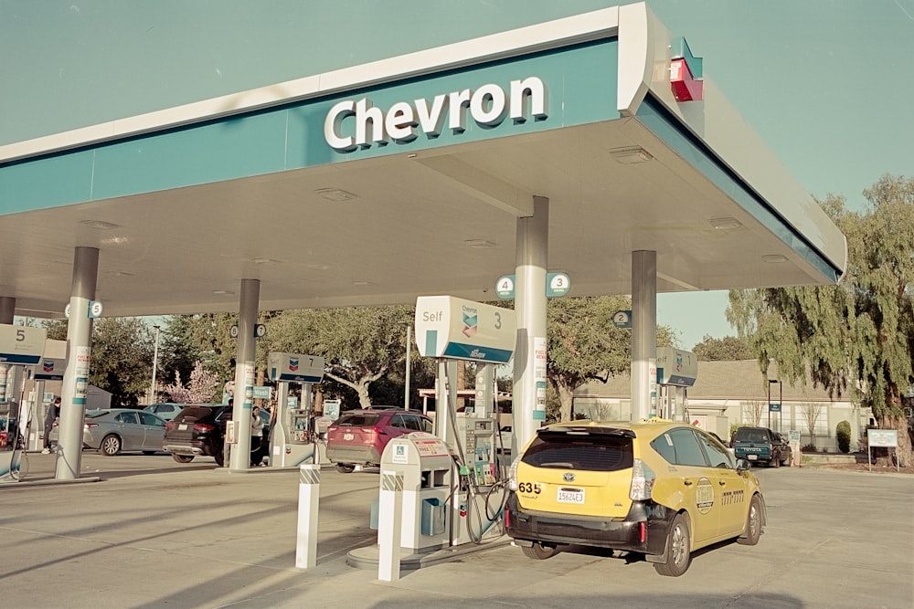 a yellow car is parked at a chevron gas station