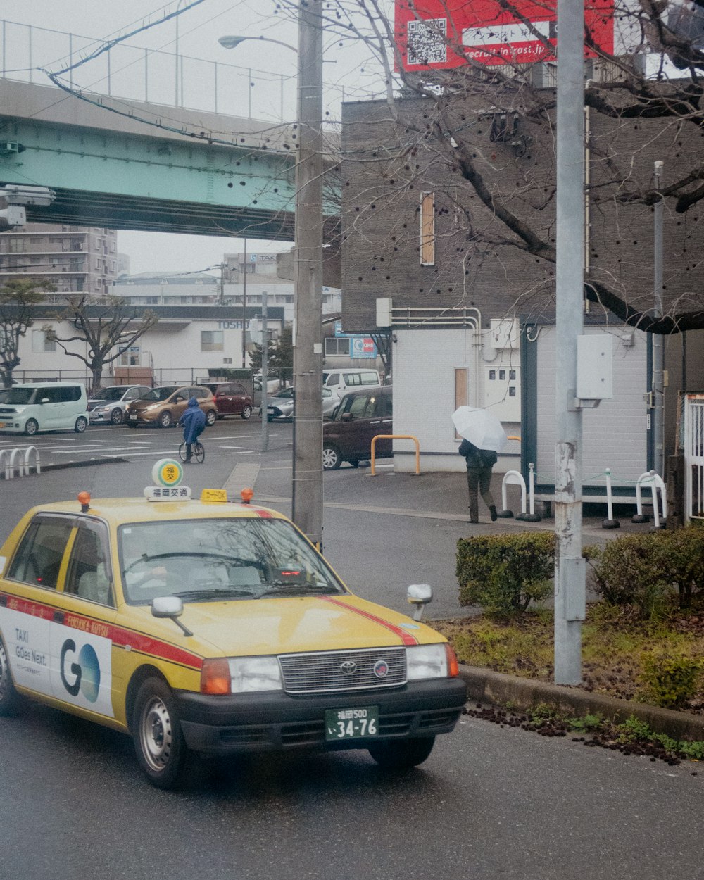 a taxi cab driving down a street next to a bridge