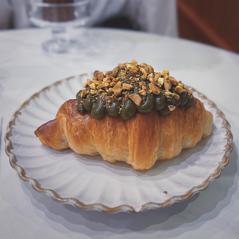 a croissant with nuts on top of it on a plate