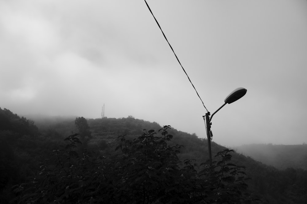 a black and white photo of a street light on a foggy day