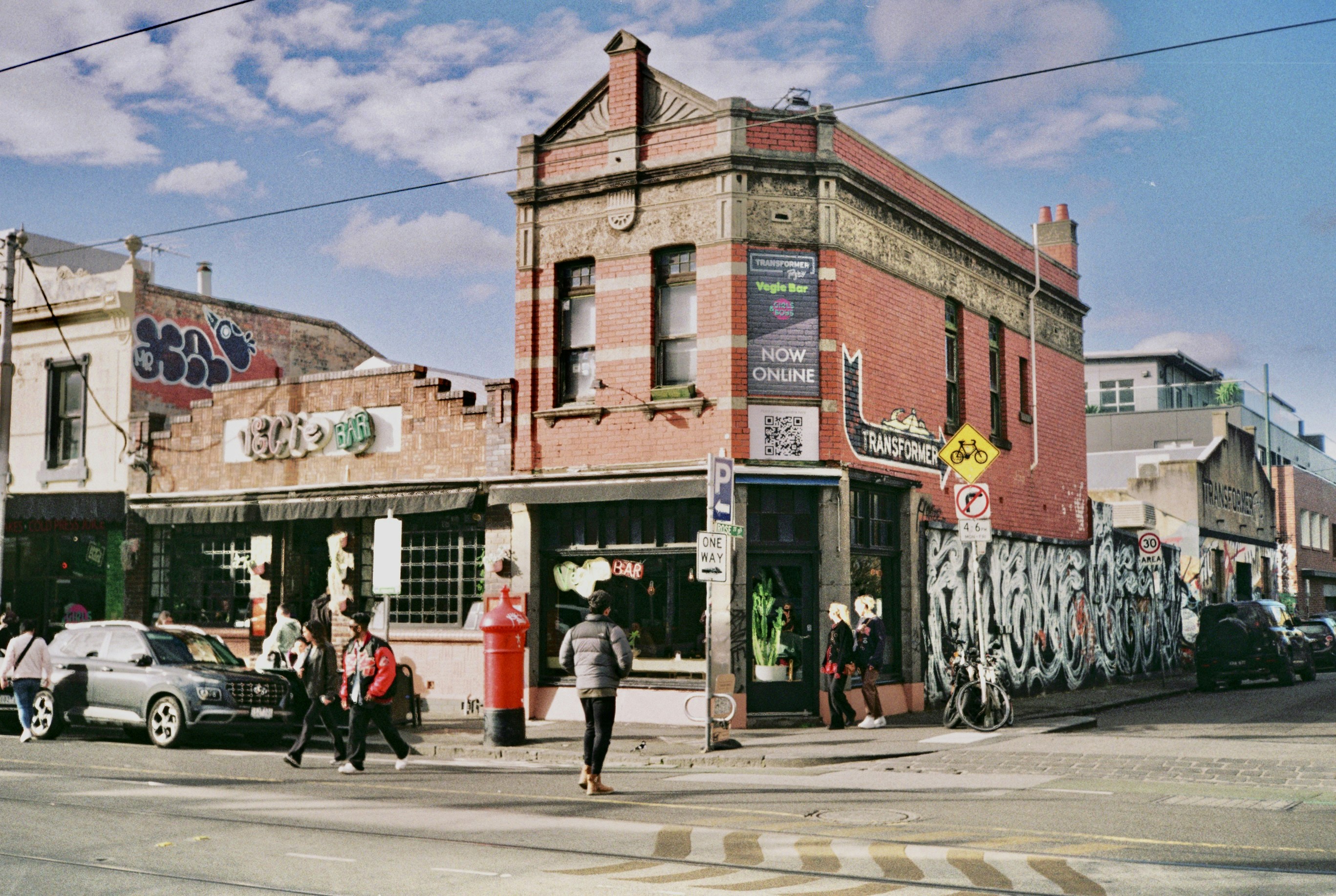 a group of people walking down a street next to a tall building, 