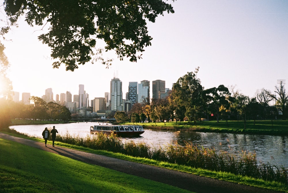 a couple of people walking down a path next to a river