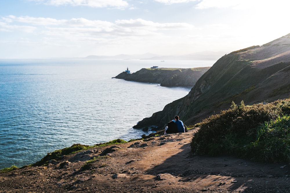 a person sitting on a cliff overlooking the ocean