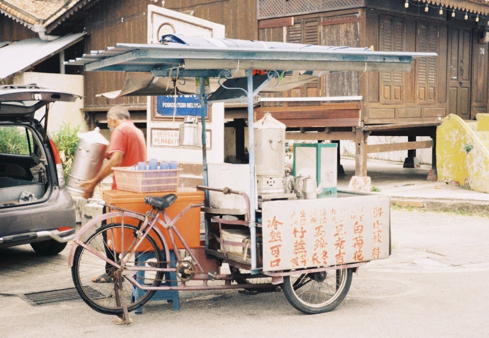 a man standing next to a bike with a cart attached to it