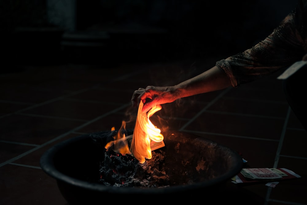a person lighting a fire in a black bowl