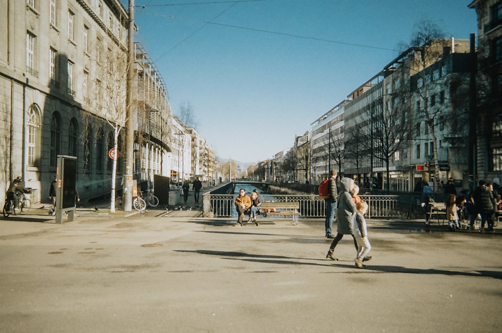 a group of people walking down a street next to tall buildings