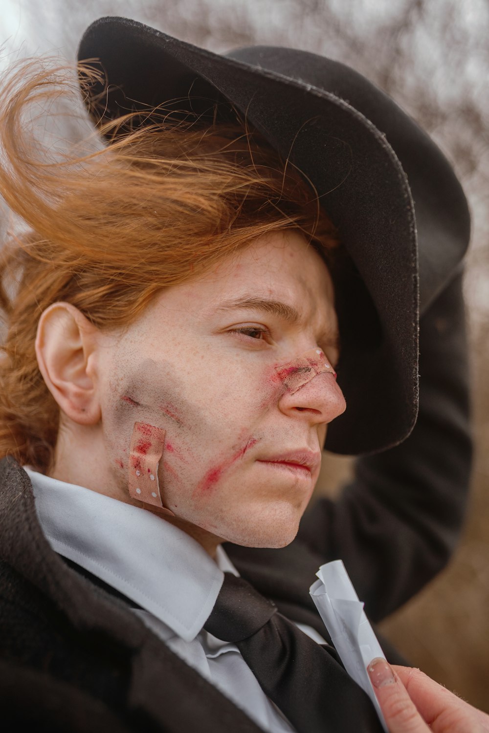 a woman in a top hat with blood on her face