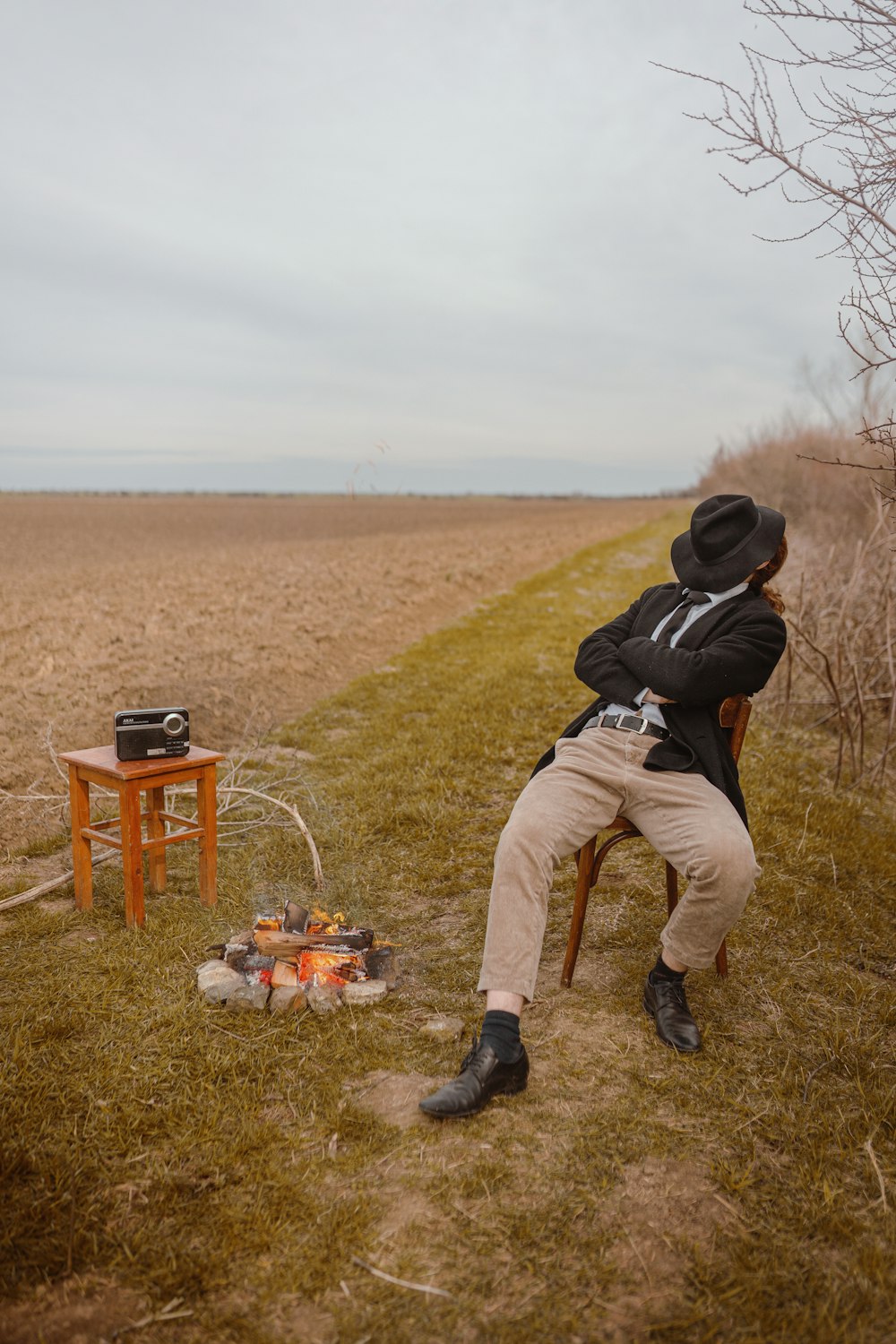 Ein Mann sitzt auf einem Stuhl neben einem Lagerfeuer