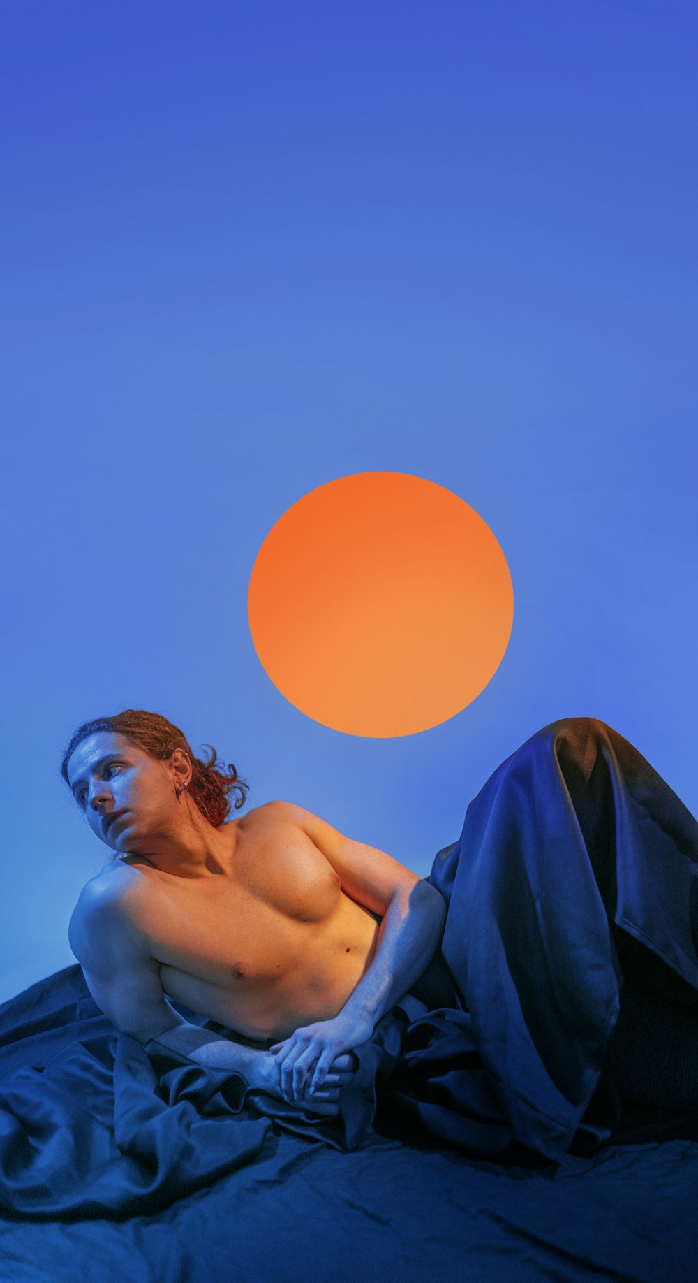 a man laying on top of a bed under a blue sky