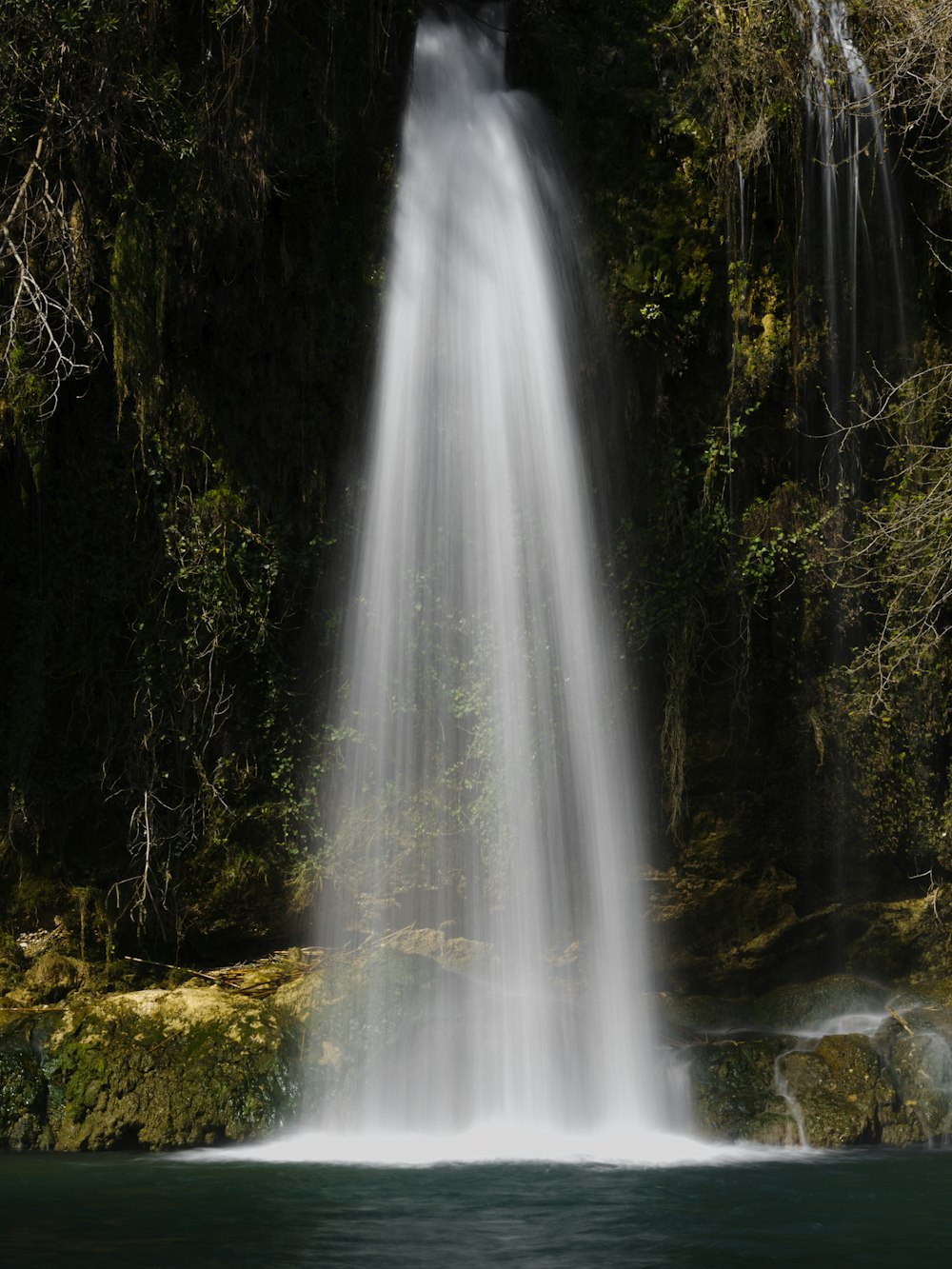 a very tall waterfall in the middle of a forest