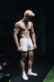a shirtless man standing in a gym