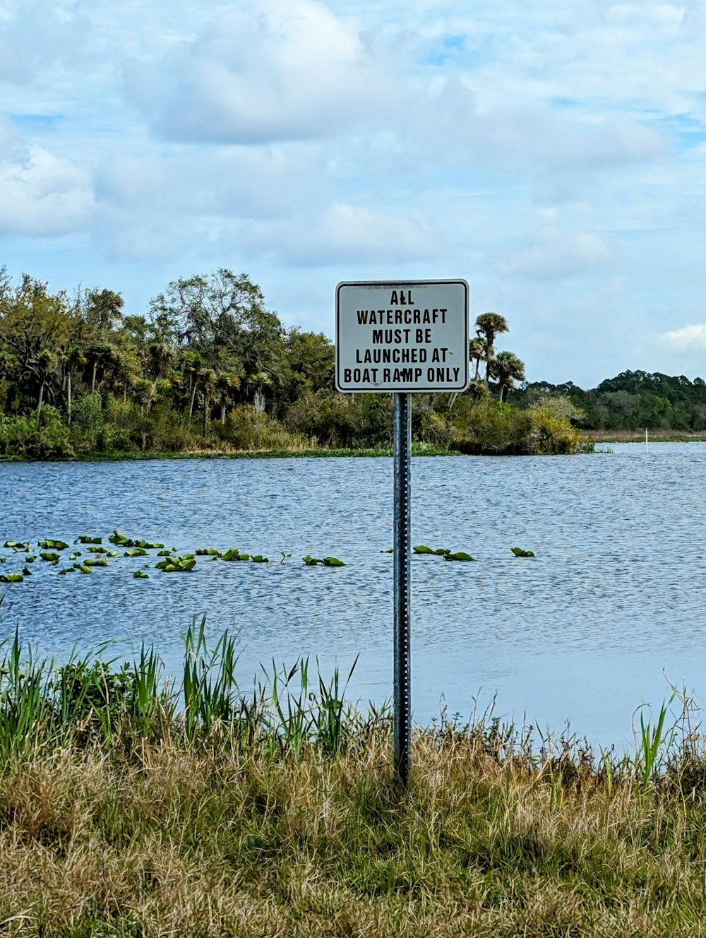 a sign on the side of a road near a body of water
