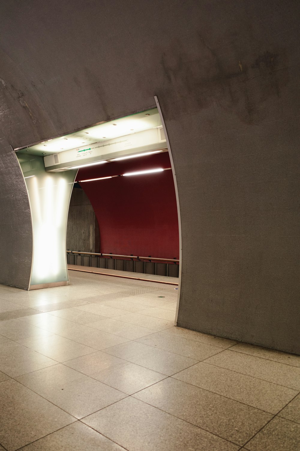 an empty subway station with a red wall