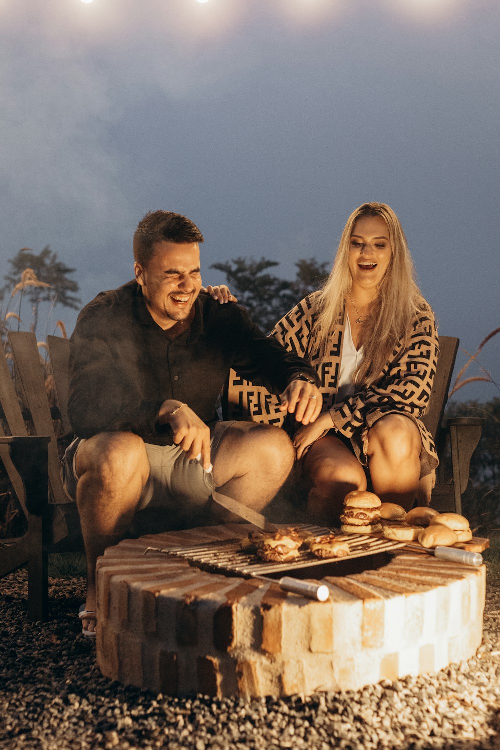 a man and a woman are sitting on a fire pit