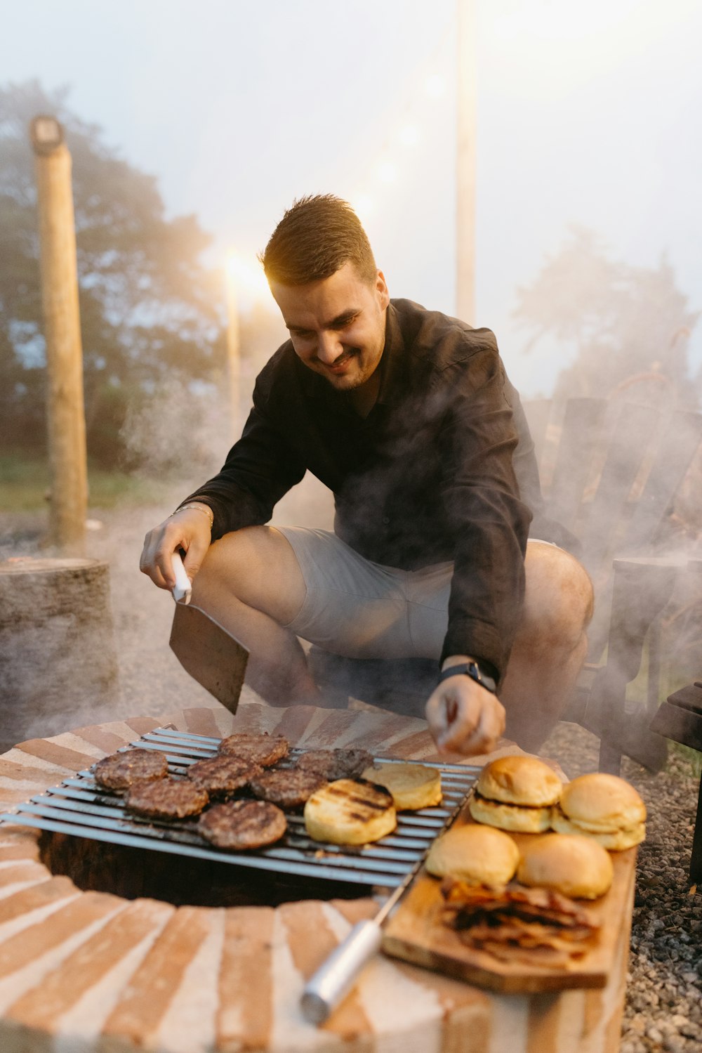 un homme faisant griller des hamburgers et des galettes de hamburger sur un gril