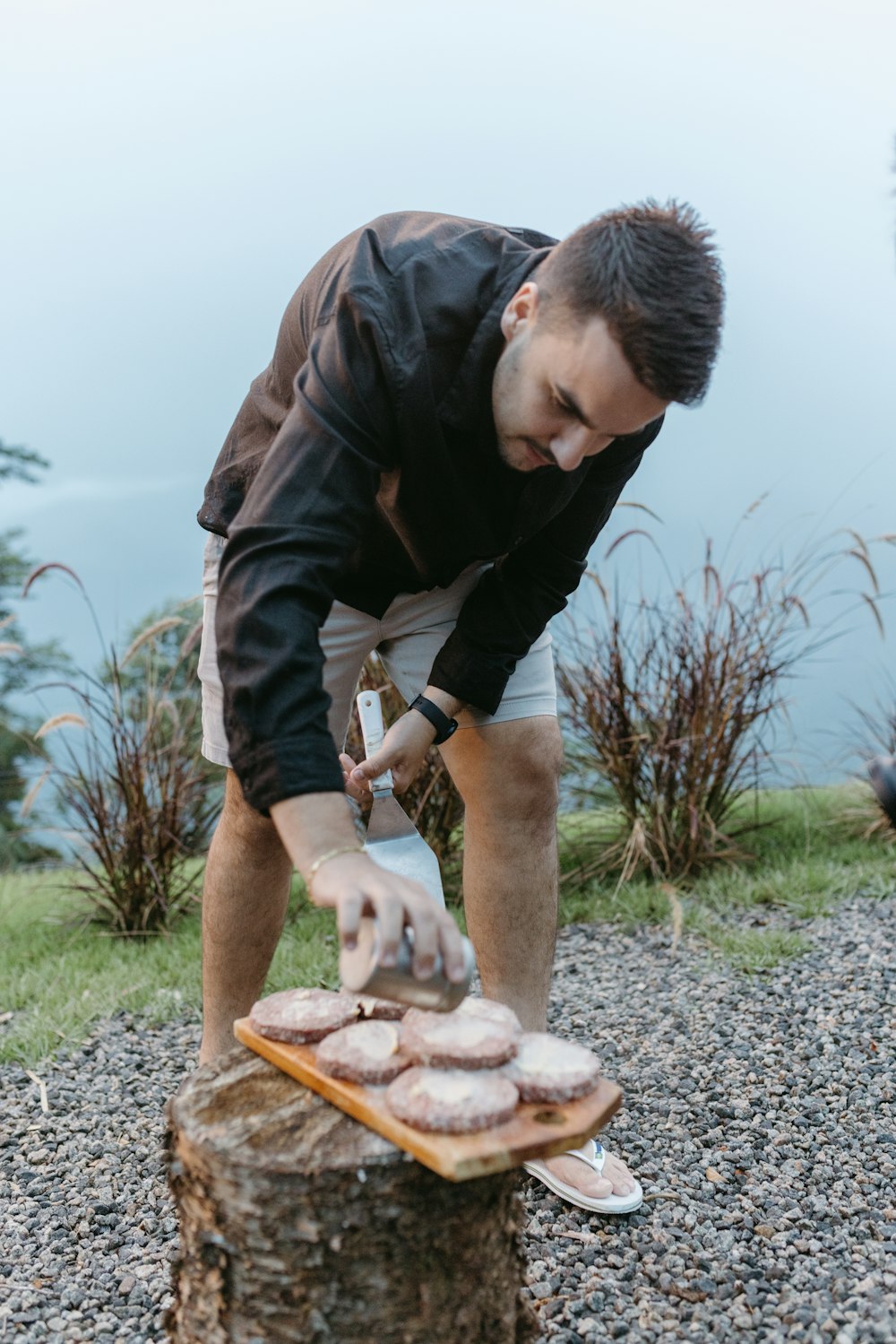 a man cutting doughnuts on top of a tree stump