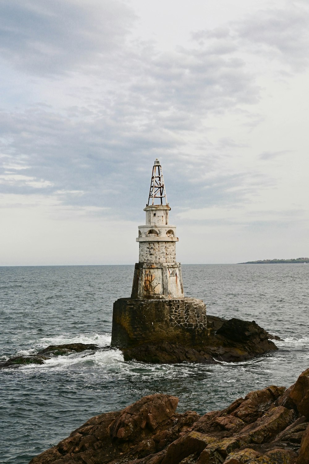a lighthouse sitting on top of a rock near the ocean