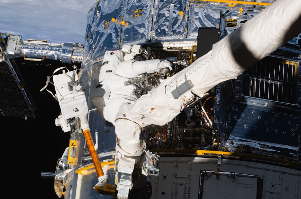 a man in a white space suit is outside of a space station