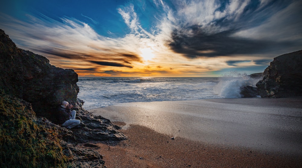 a person sitting on a beach next to the ocean