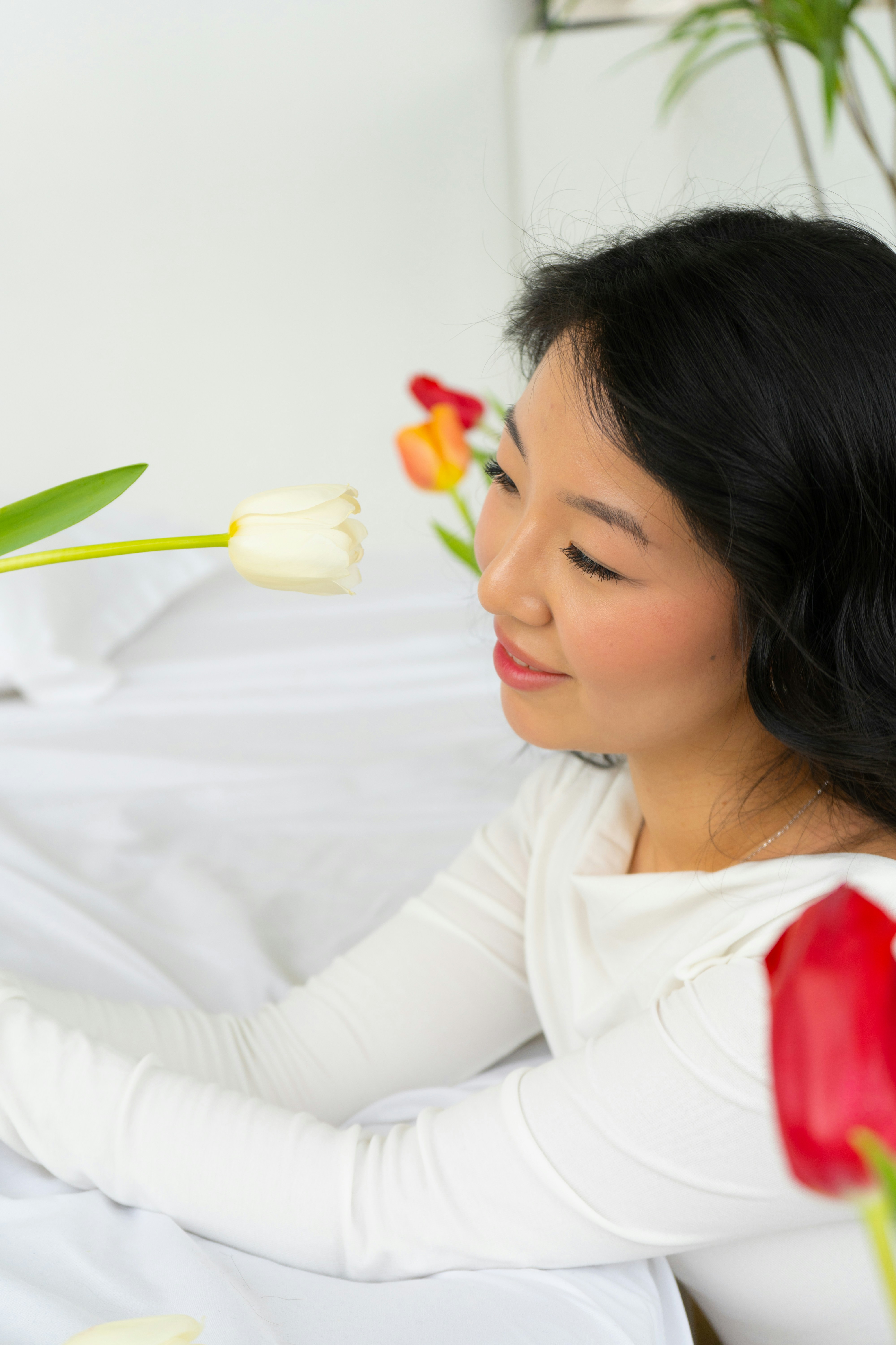 seorang wanita duduk di tempat tidur dengan bunga di tangannya
