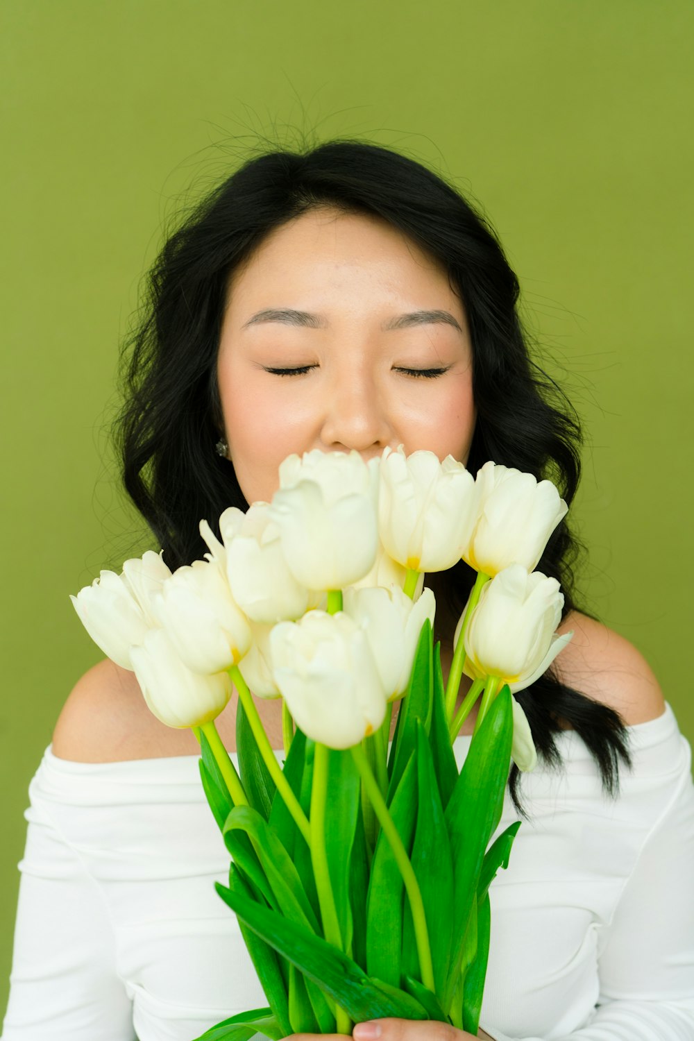 白いチューリップの花束を持つ女性