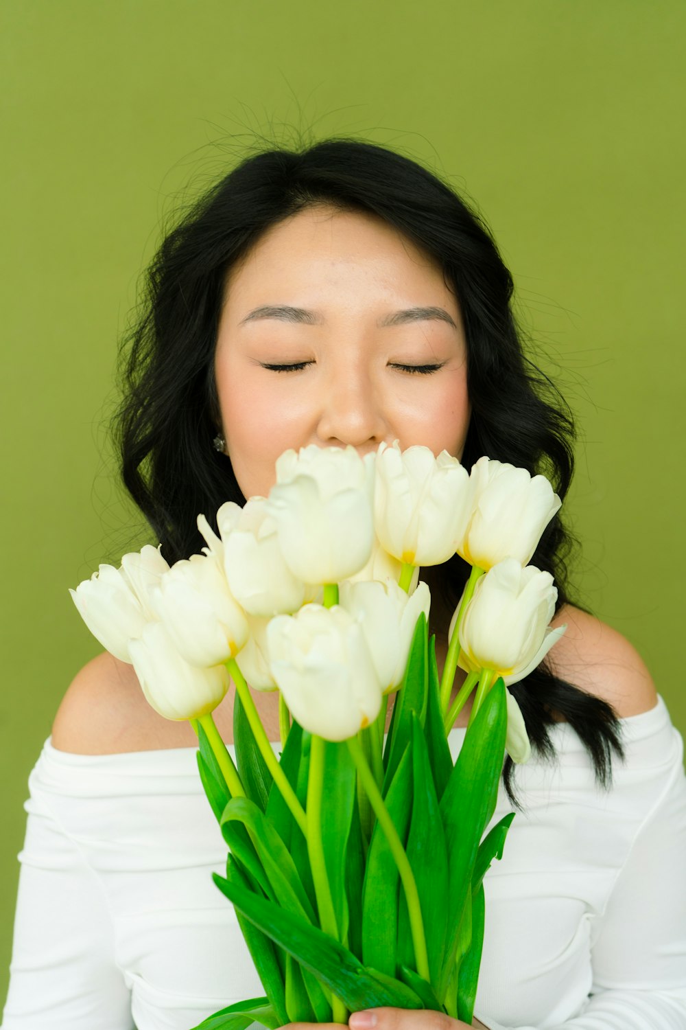 a woman holding a bouquet of white tulips