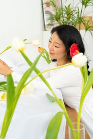 a woman sitting at a table with flowers in a vase