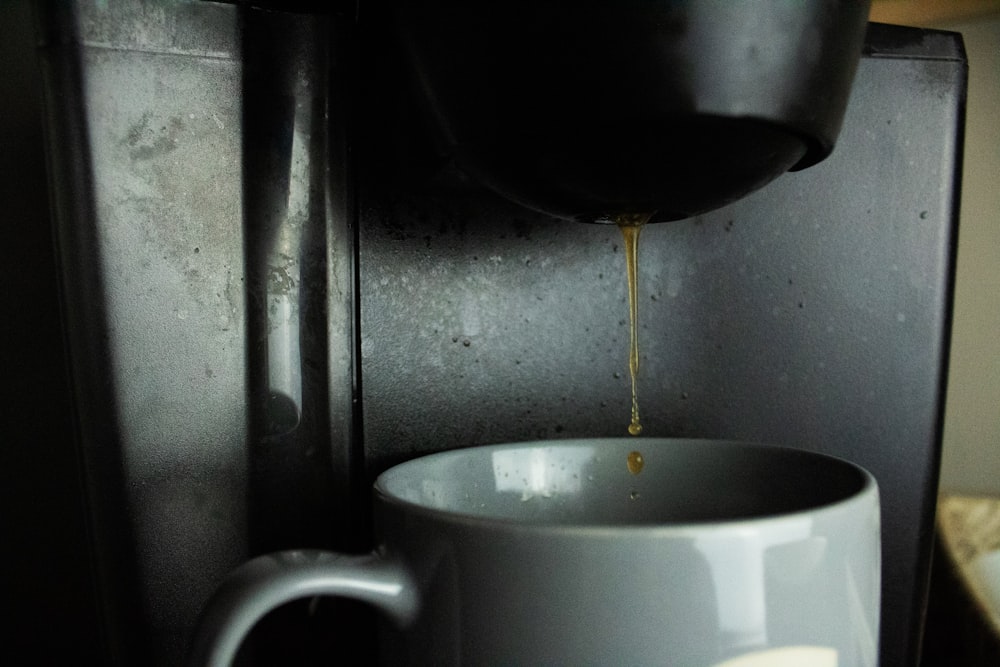 a cup of coffee being poured into a coffee maker