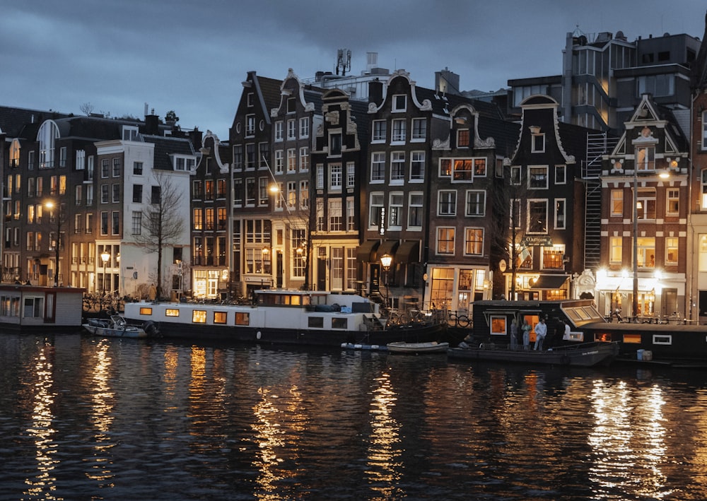 a group of boats floating on top of a river next to tall buildings