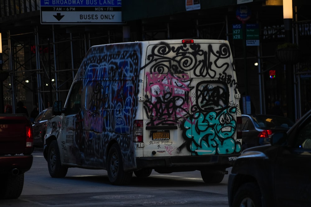 a van covered in graffiti driving down a street