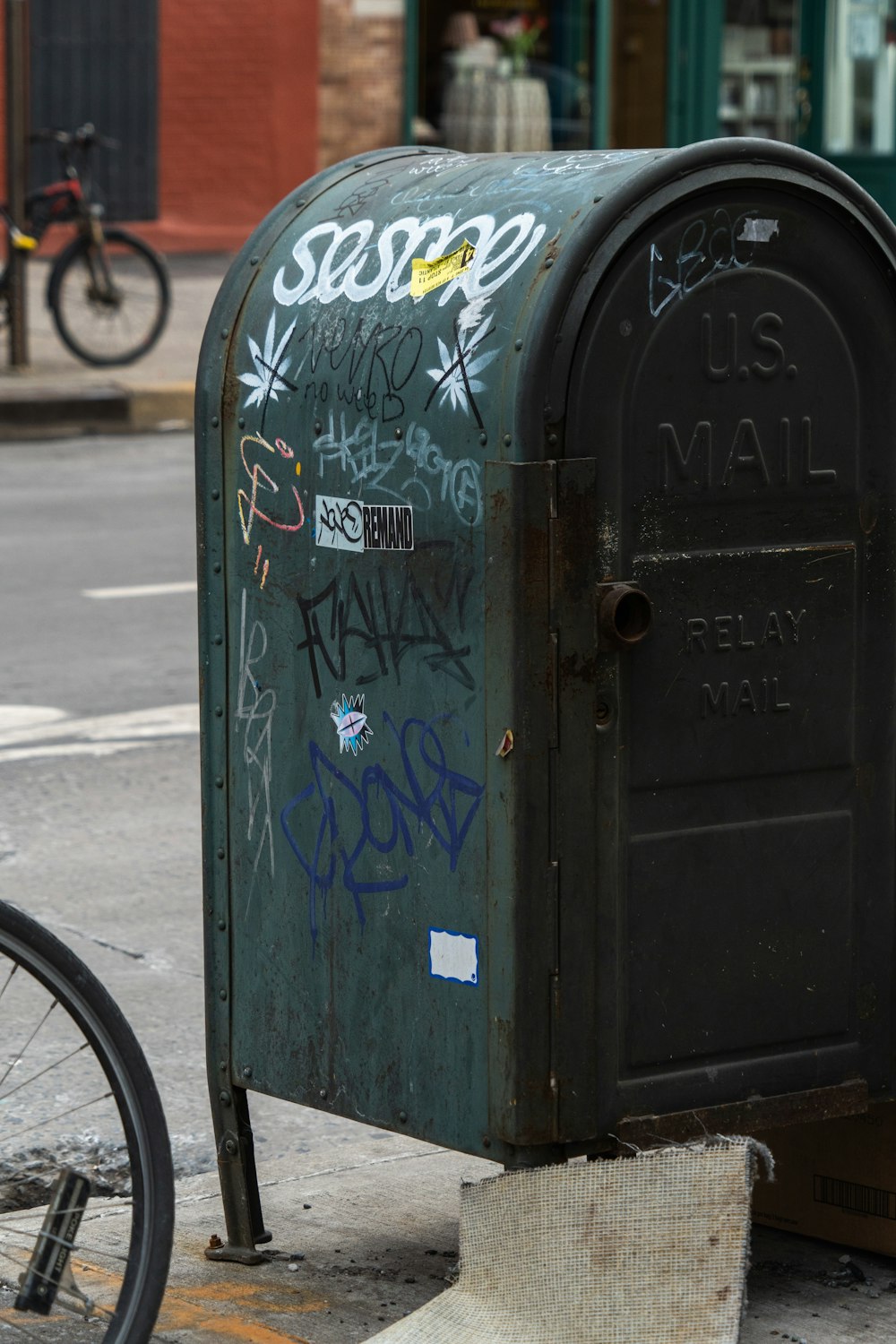 uma caixa de correio com pichações ao lado de uma bicicleta