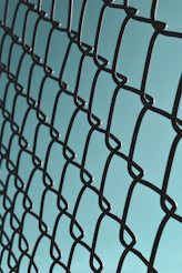 a close up of a metal fence with a blue sky in the background