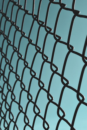 a close up of a metal fence with a blue sky in the background