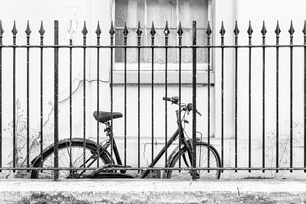 uma bicicleta estacionada ao lado de uma cerca em frente a um prédio