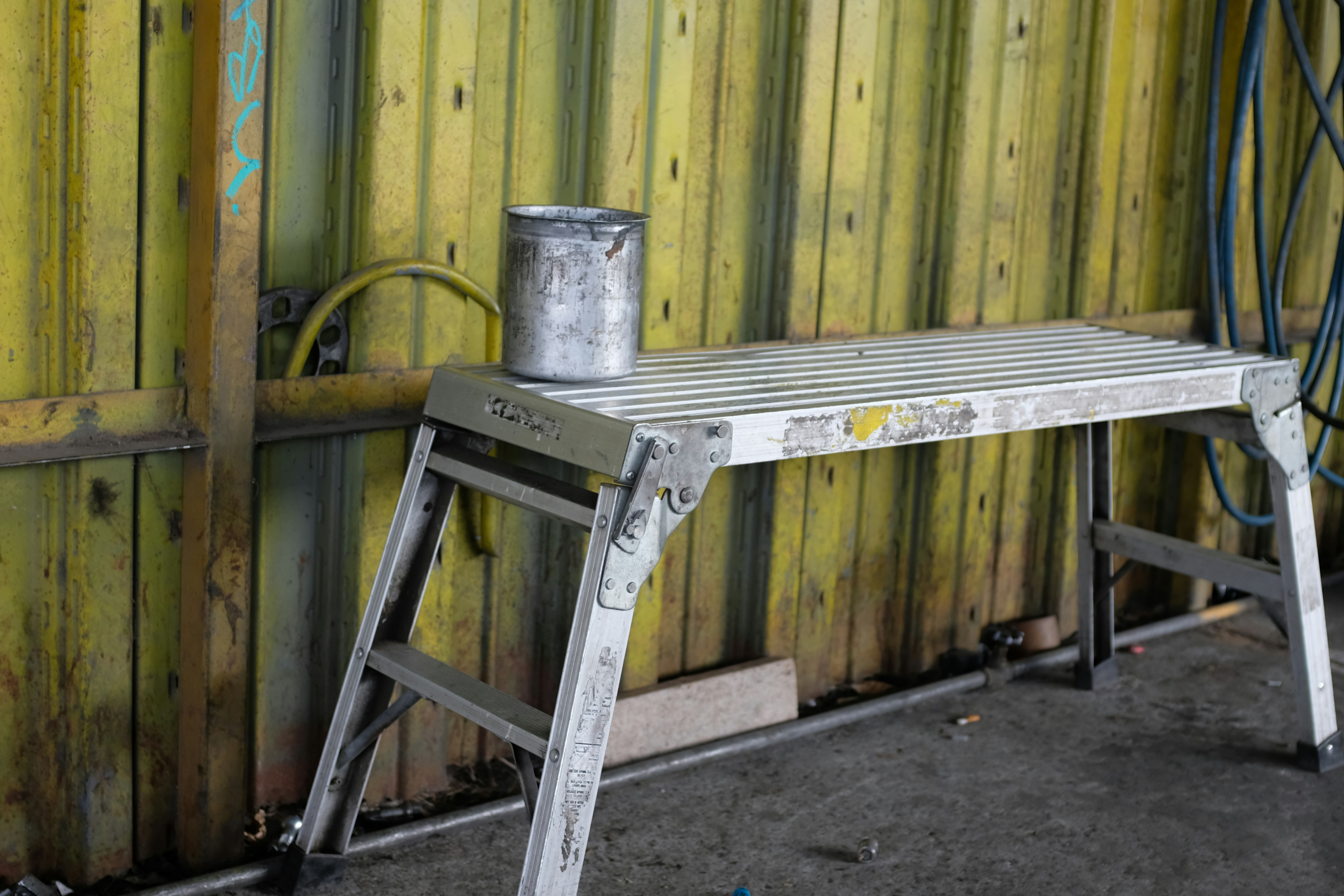 un taburete de metal sentado junto a una pared de madera