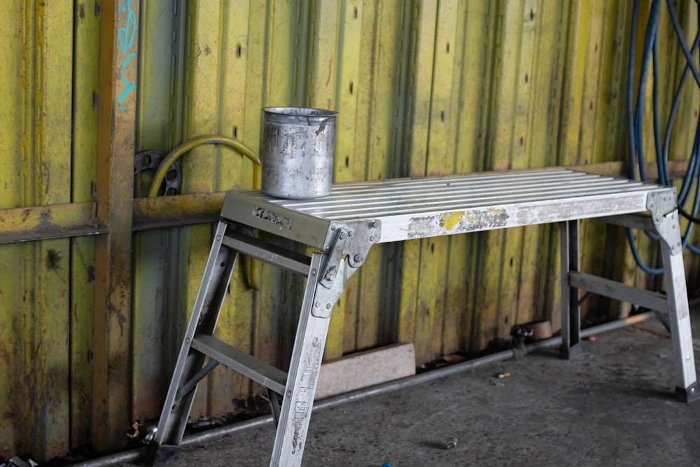 un taburete de metal sentado junto a una pared de madera