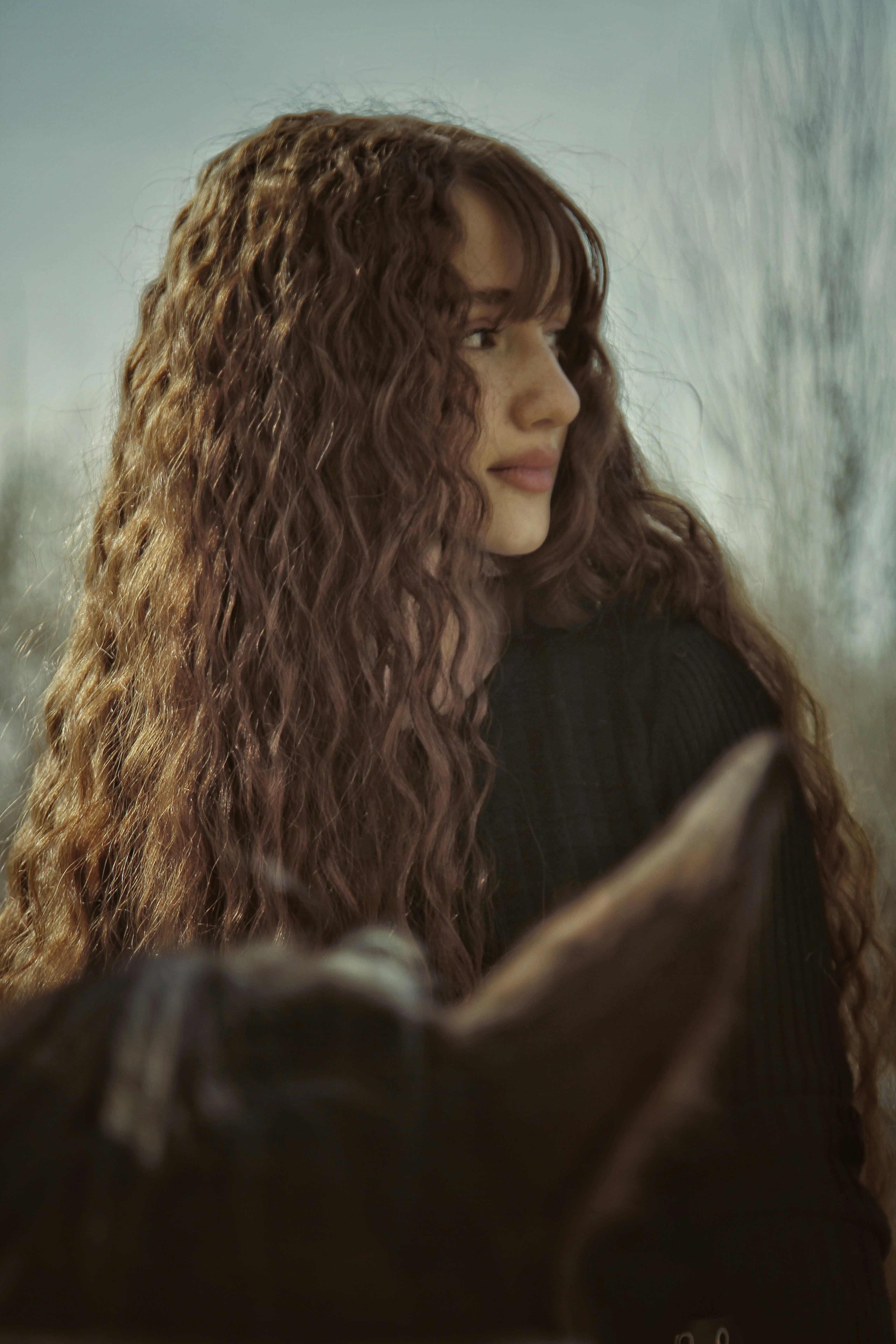 A woman with long curly hair standing in a field photo – Free Woman ...