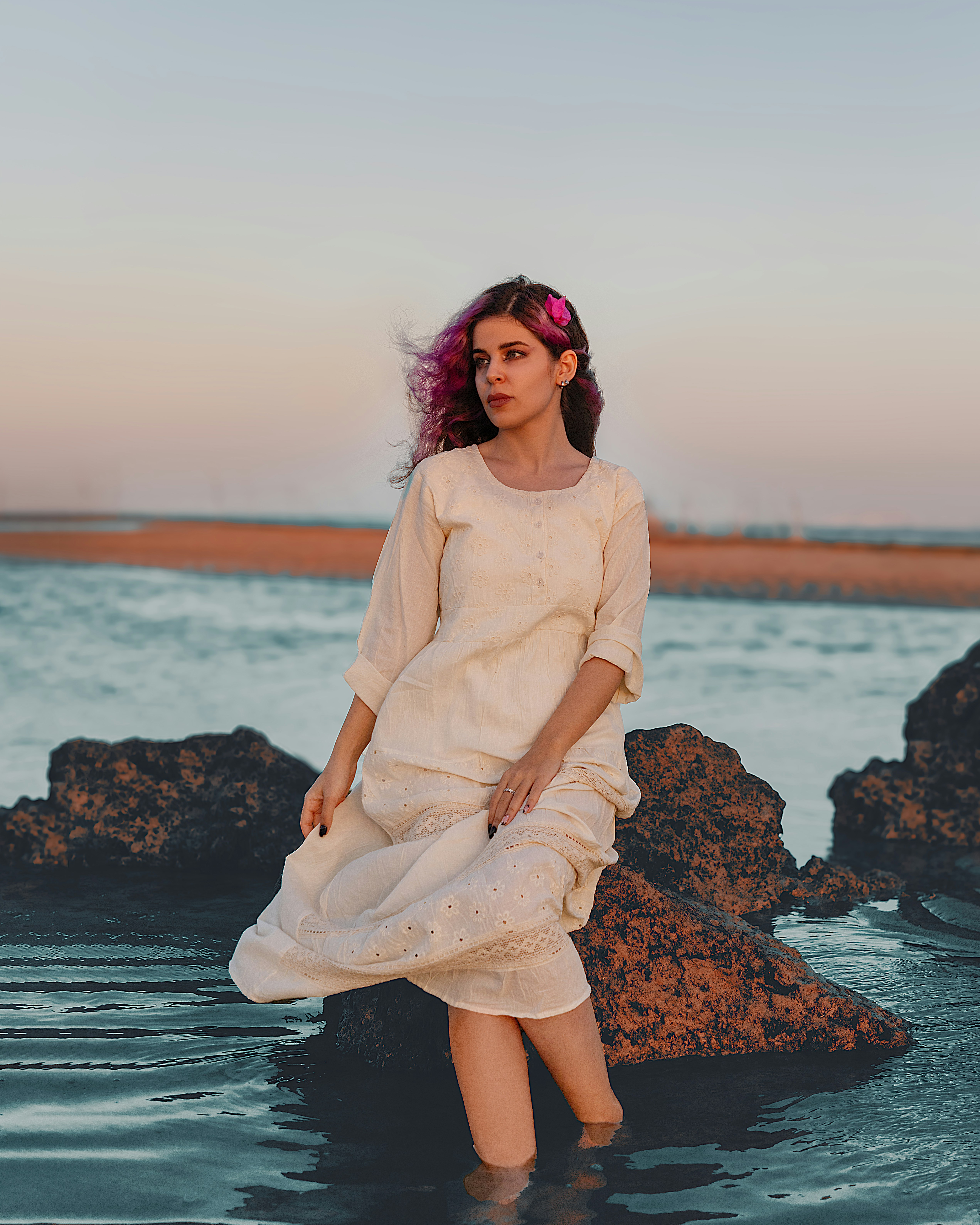 a woman in a white dress standing in the water