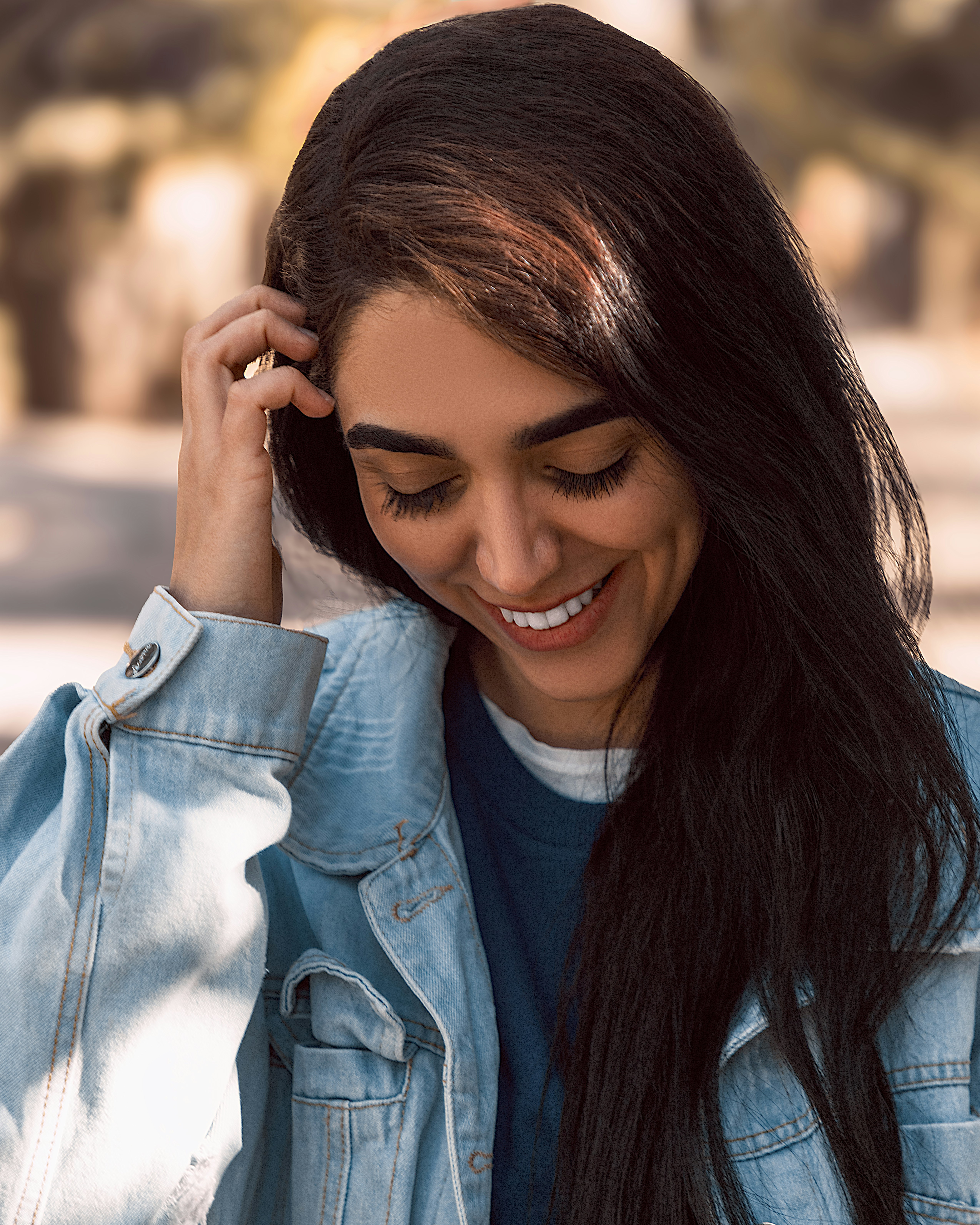 a woman with long black hair smiling and holding a cell phone to her ear