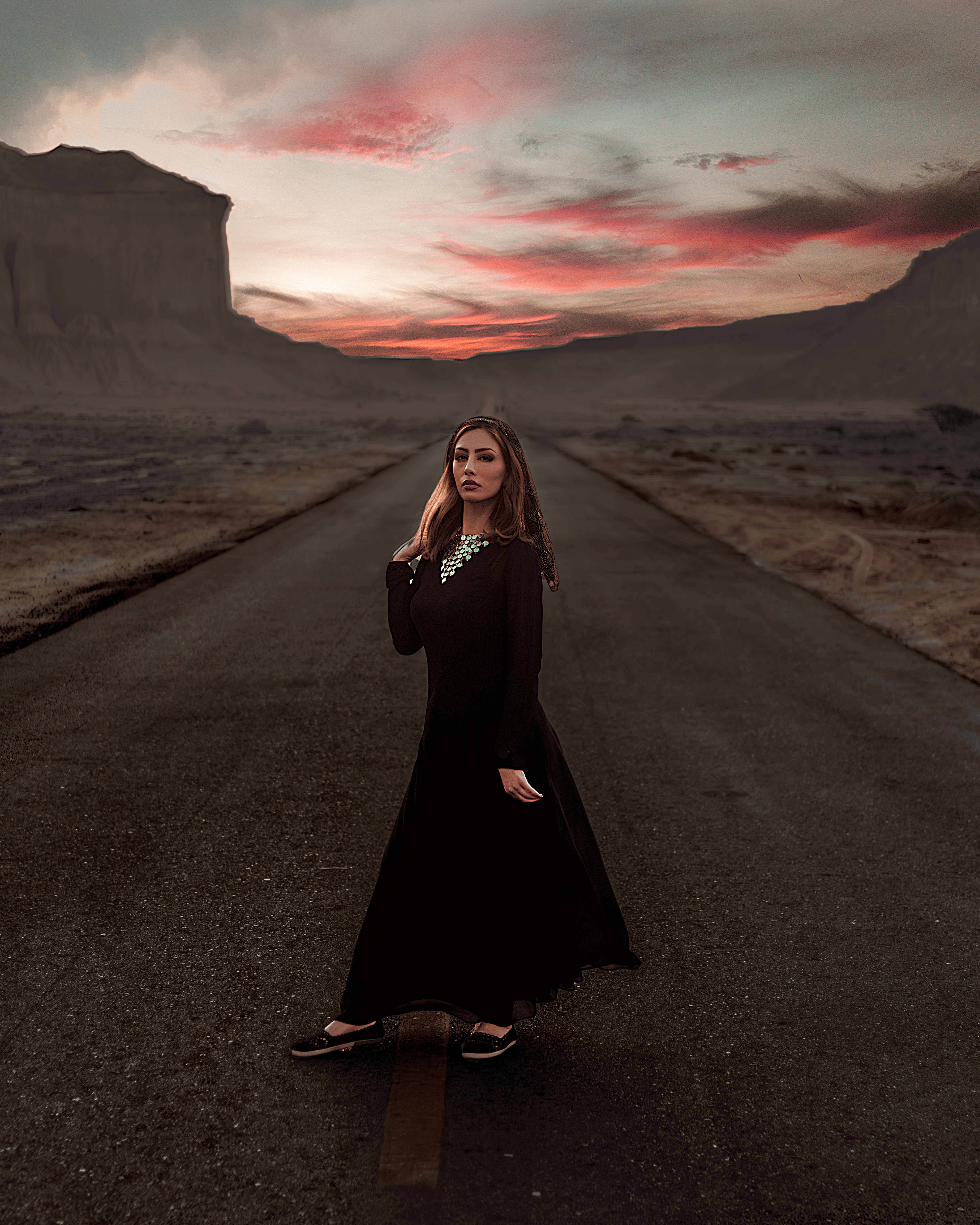 a woman in a black dress standing on a road