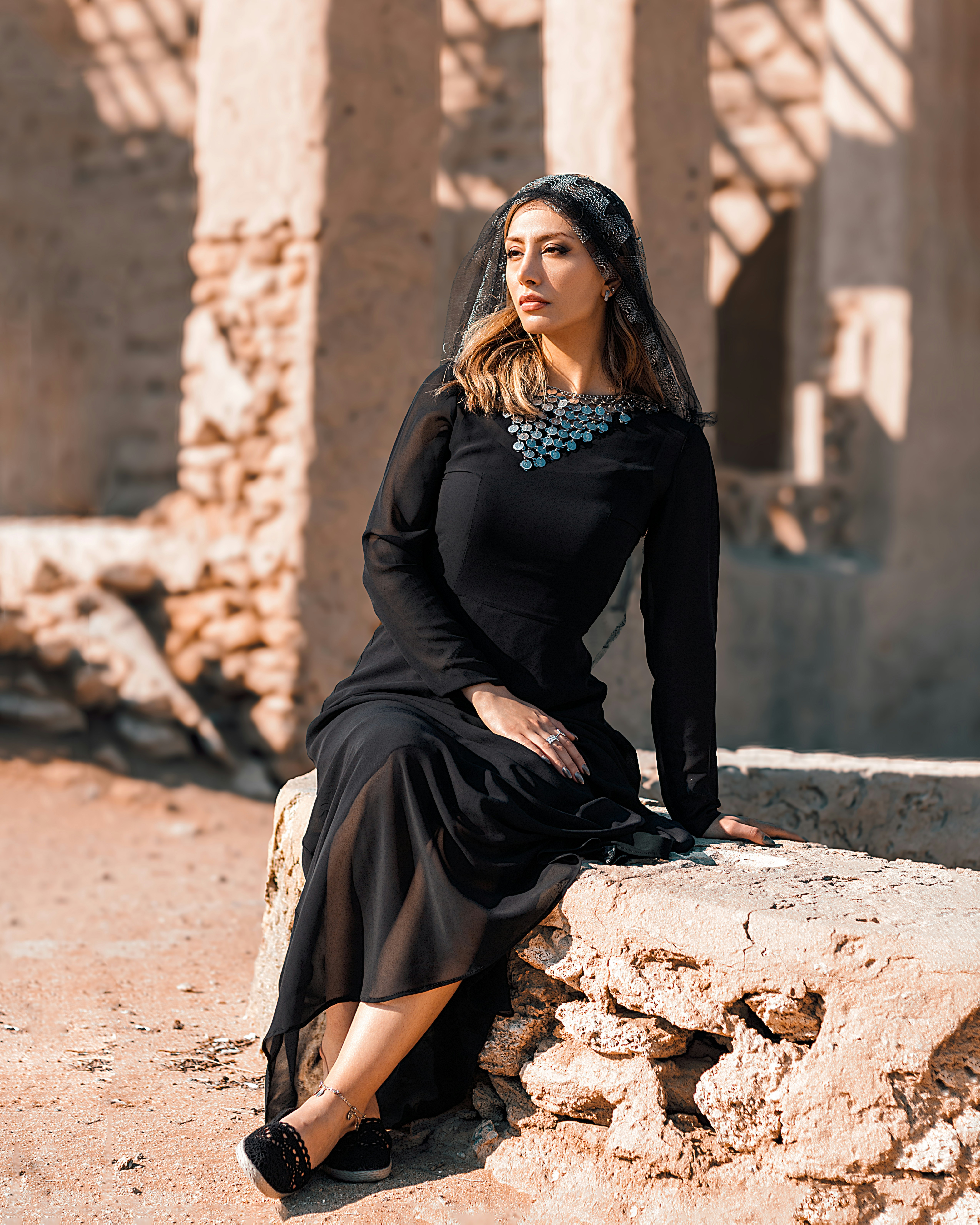 a woman in a black dress sitting on a rock