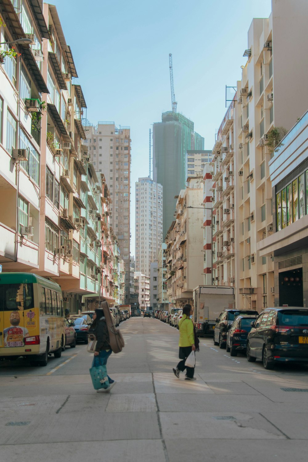 a couple of people walking down a street next to tall buildings