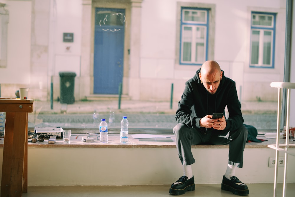 a man sitting on a ledge looking at his cell phone