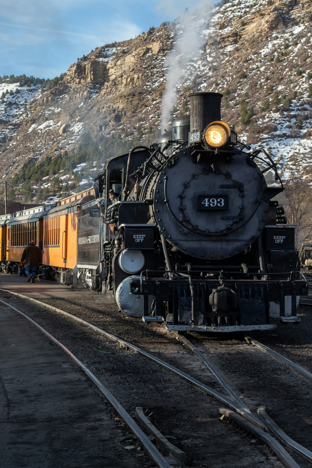 a train traveling down train tracks next to a mountain