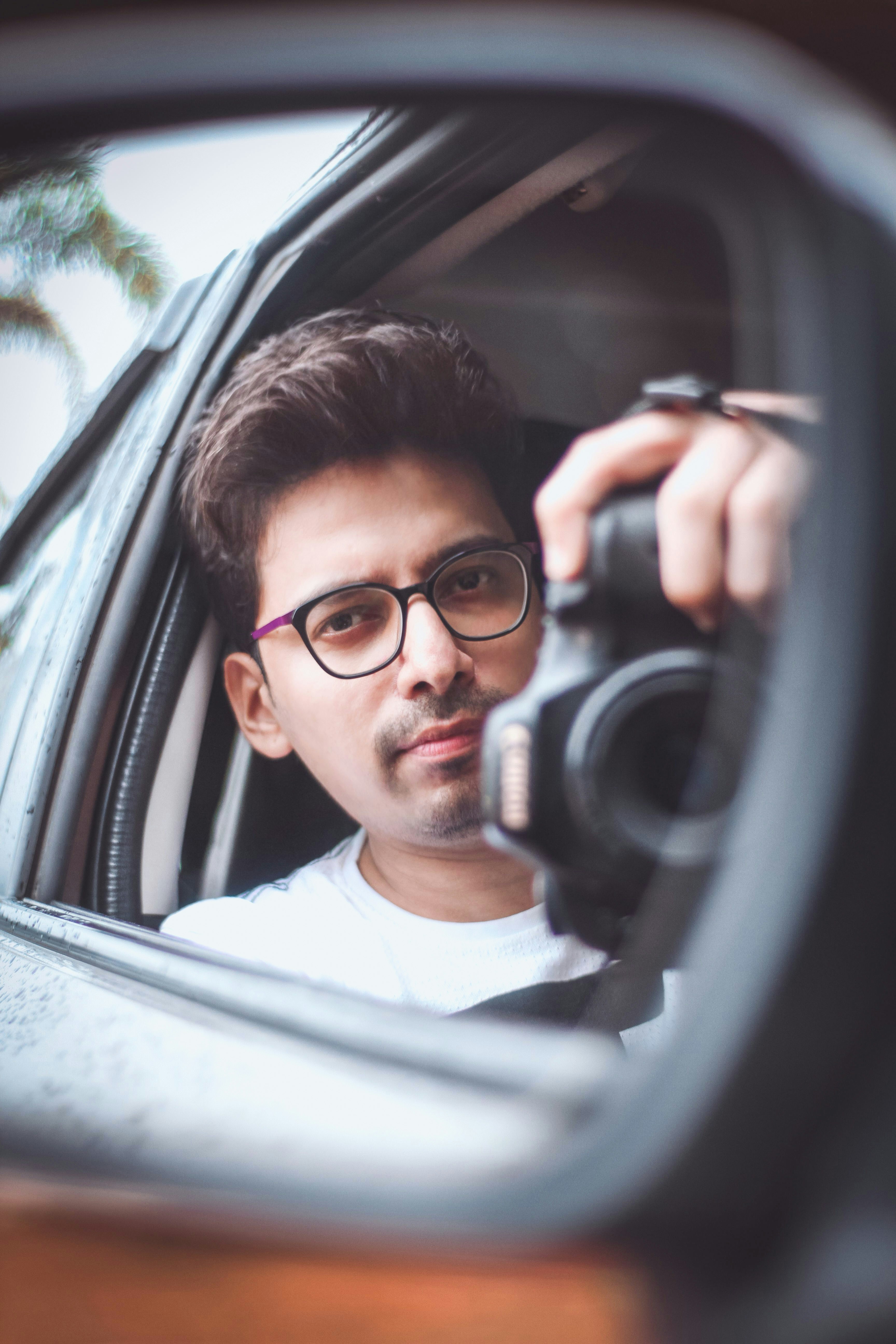 a man taking a picture of himself in a car mirror