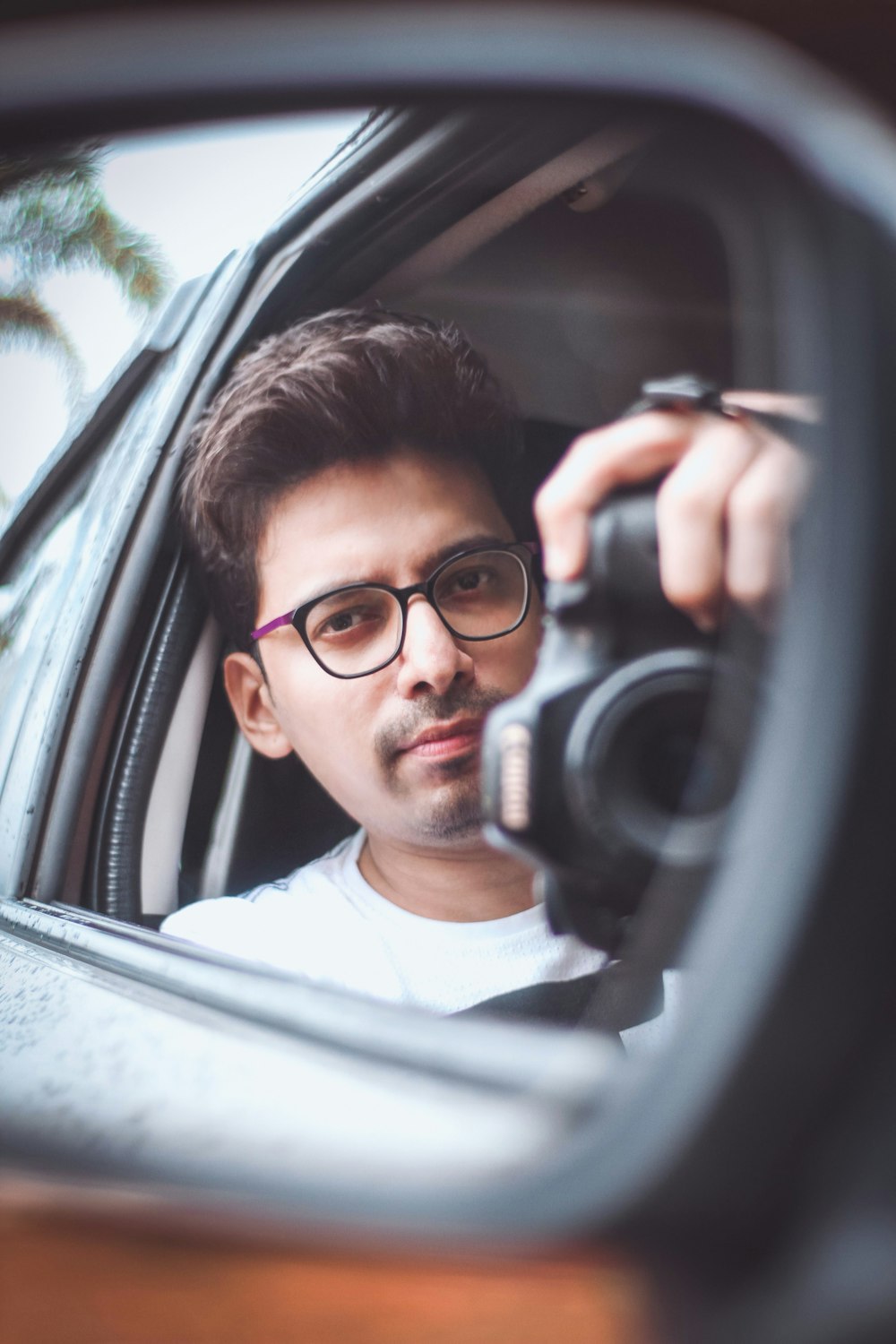 a man taking a picture of himself in a car mirror