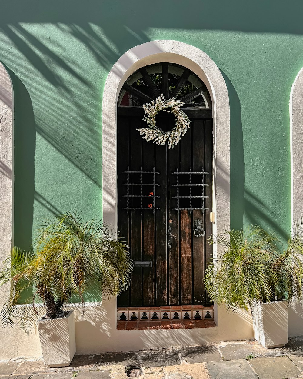 a green building with a door and a wreath on it