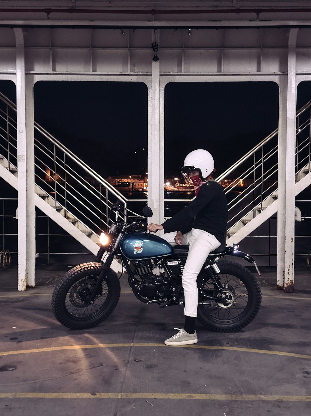 a person sitting on a motorcycle in a parking lot